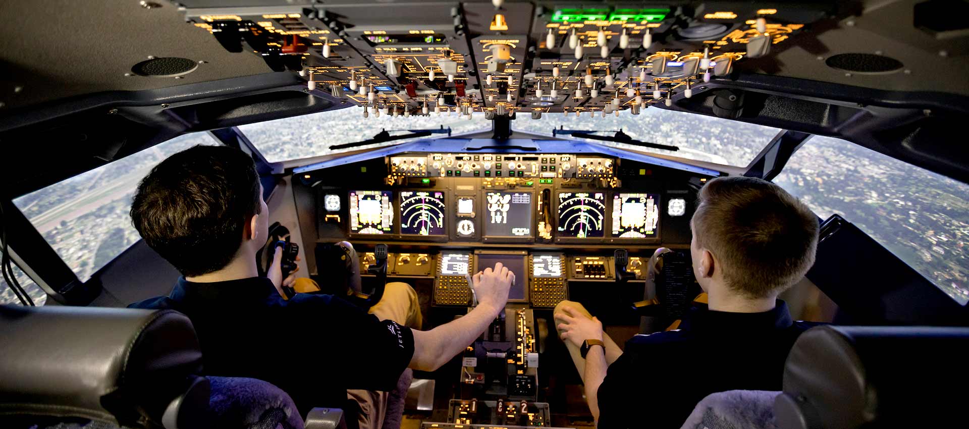 Two students sitting in the cockpit of a flight simulator