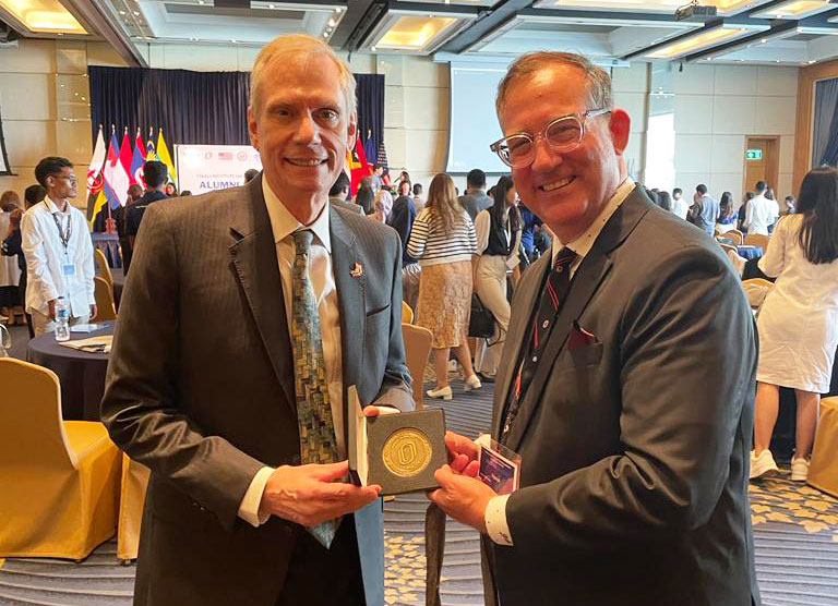 Dr. Patrick McNamara gifts a UNO Medallion to Ambassador Robert Godec