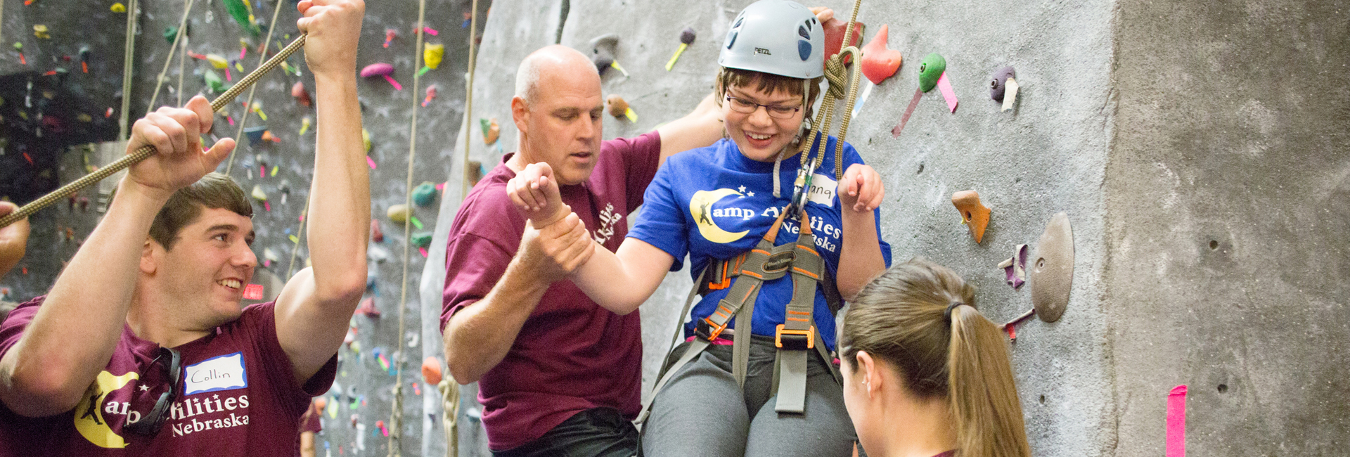 A Camp Abilities student is all smiles after scaling UNO's climbing wall.