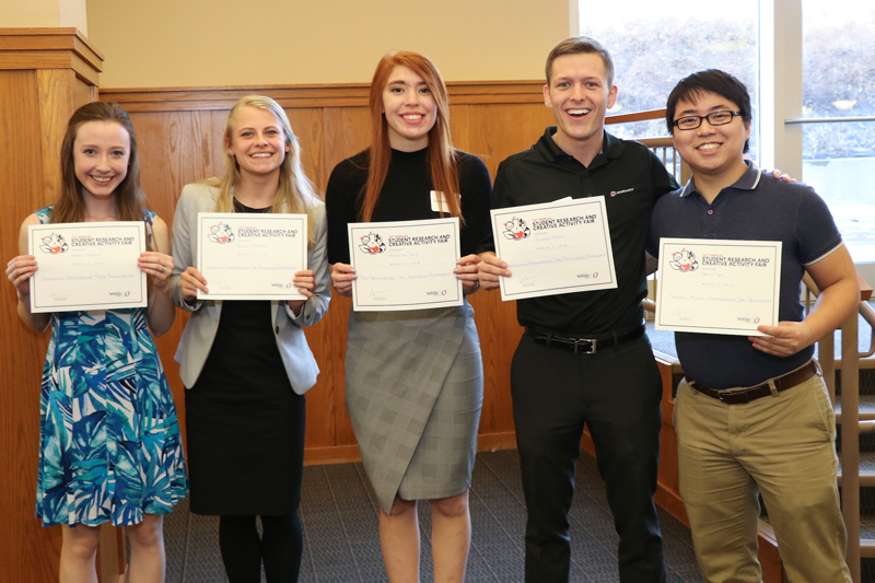 Sack (center) stands with other students recognized at the Student Research and Creative Activity Fair, including fellow Goldwater scholars Zachary Meade and Harim Won.