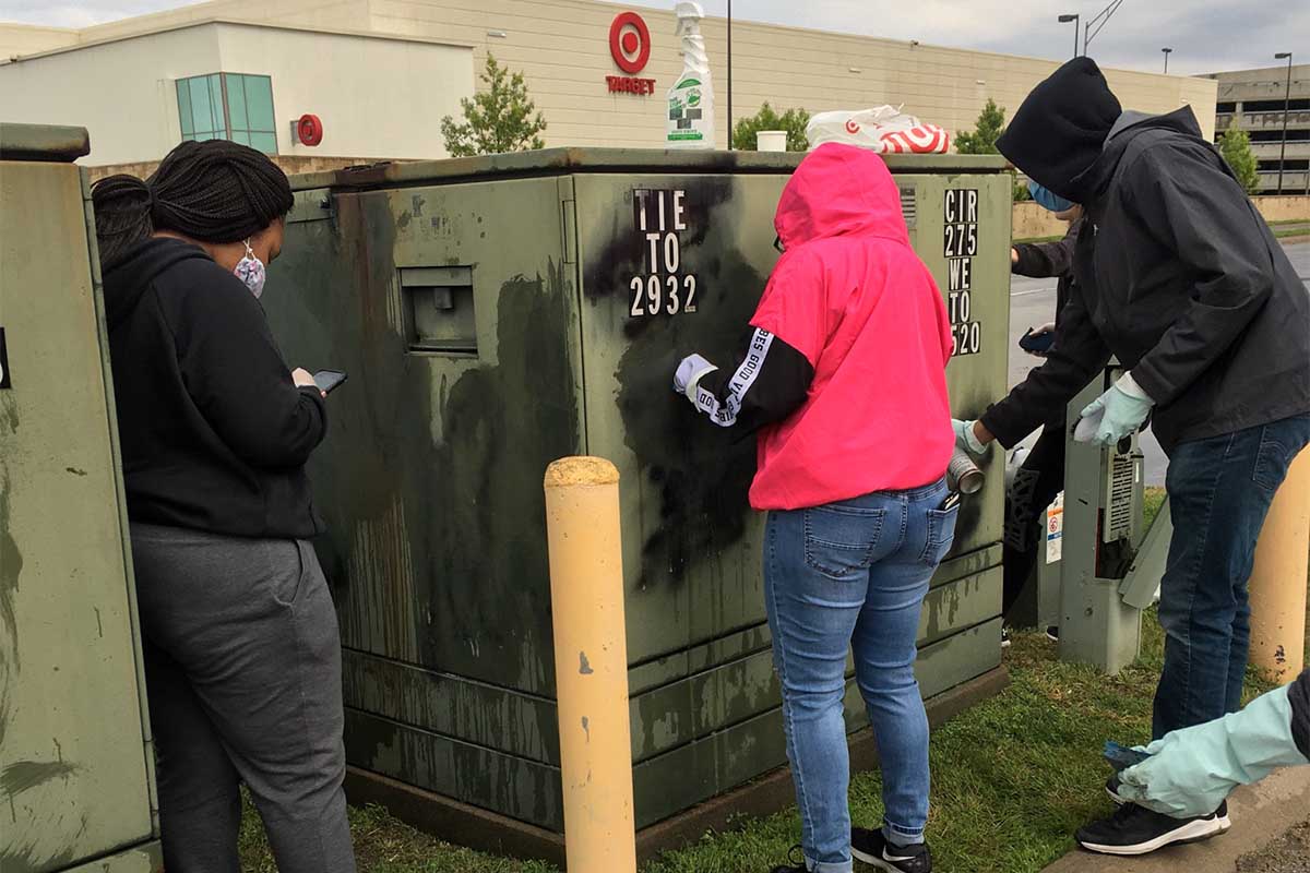 Students scrub graffiti near 72nd and Dodge in Omaha.