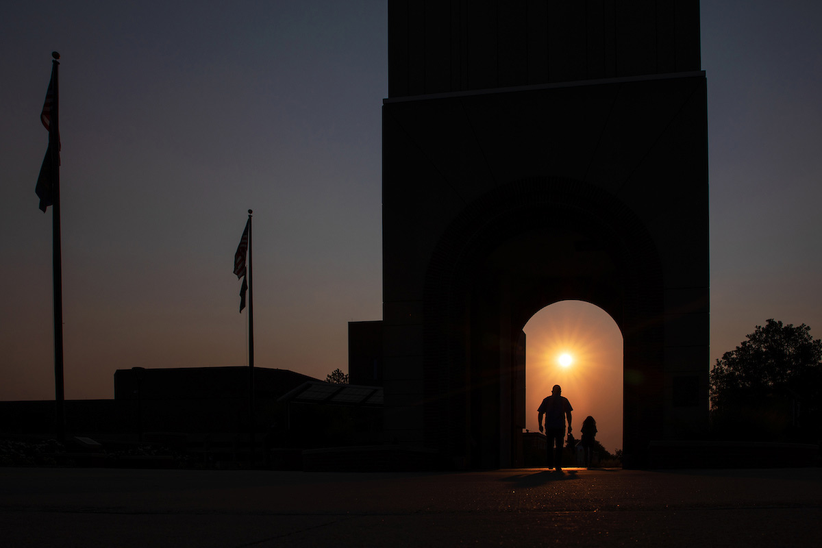 A student walks under the bell tower at sunrise