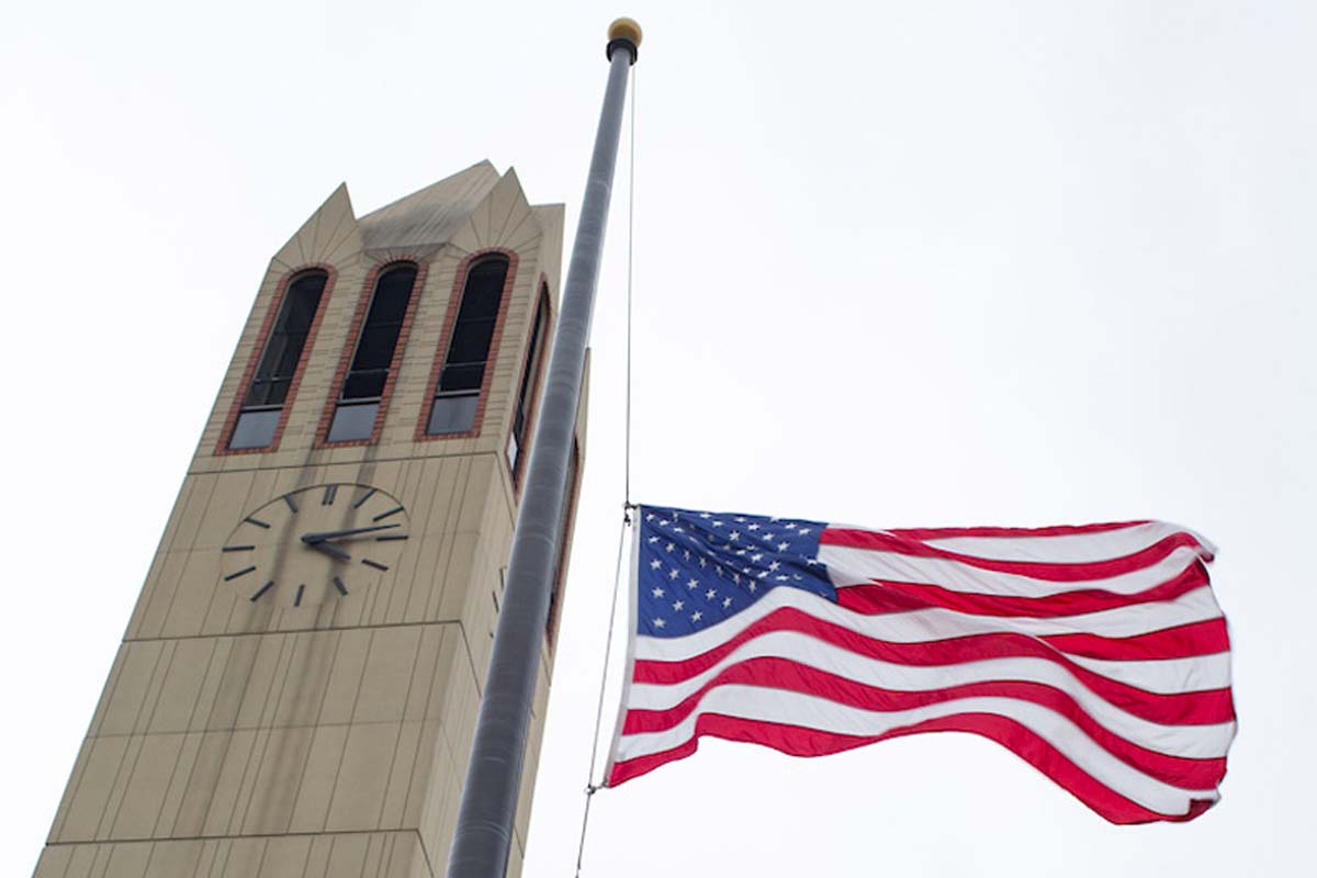 The American flag is lowered to half mast next to the Henningson Memorial Campanile