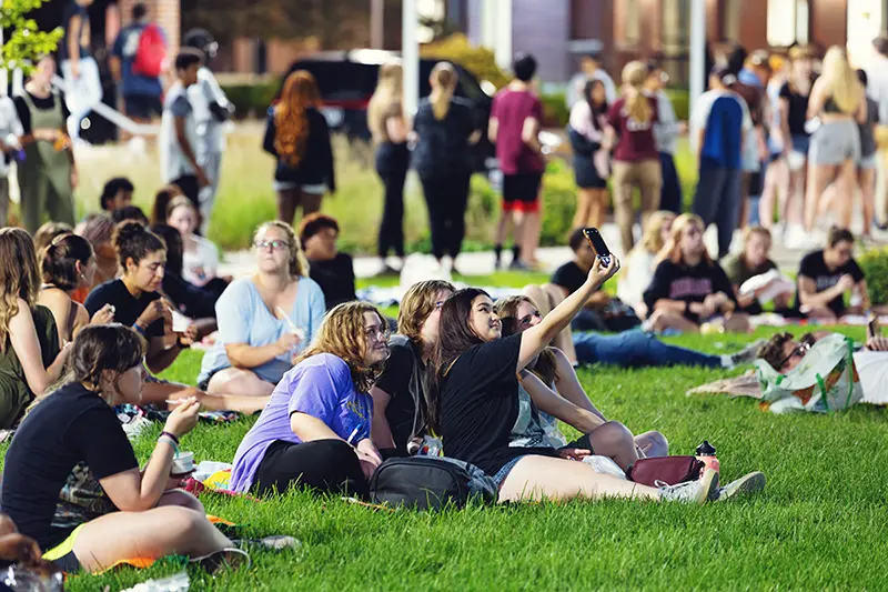 students gathered on blankets in the grass for an outdoor movie night