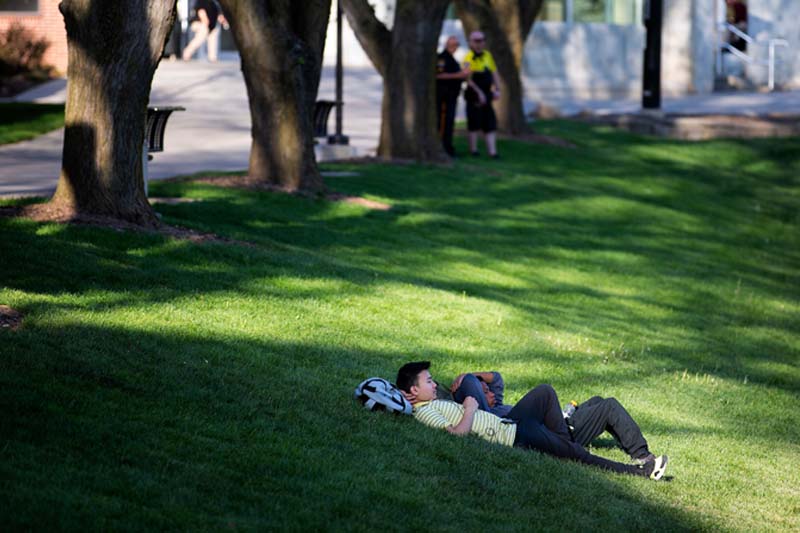 A student relaxes in the shade at the Pep Bowl
