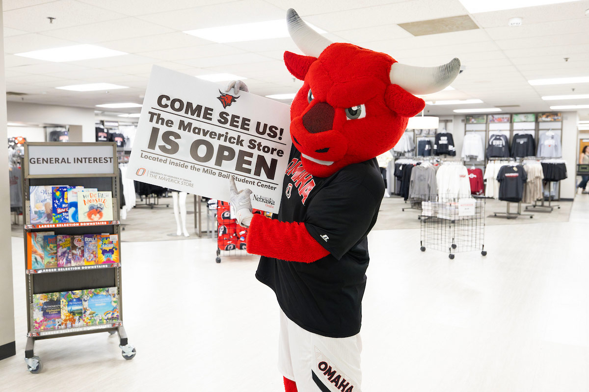 UNO’s Durango mascot holds a sign reading “Come See Us, the Maverick Store is Open.” 