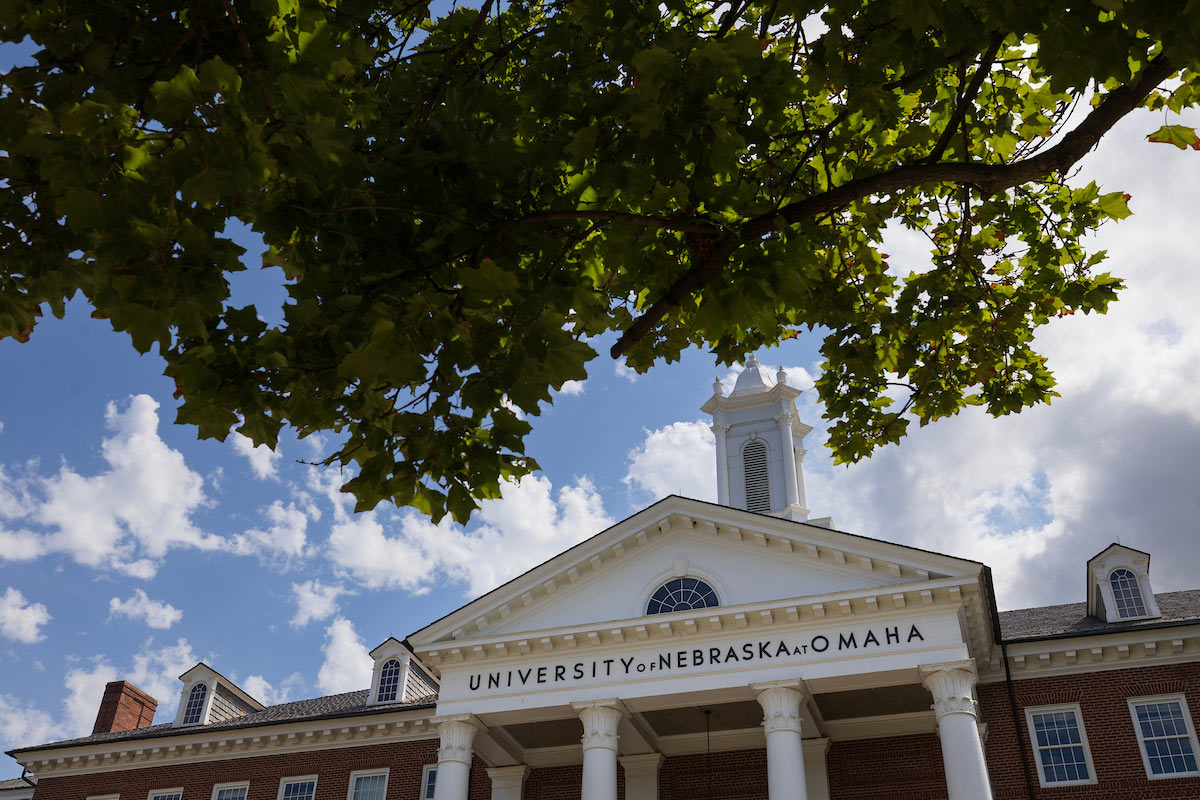 Sun shines through a tree in front of the Arts and Sciences Hall.