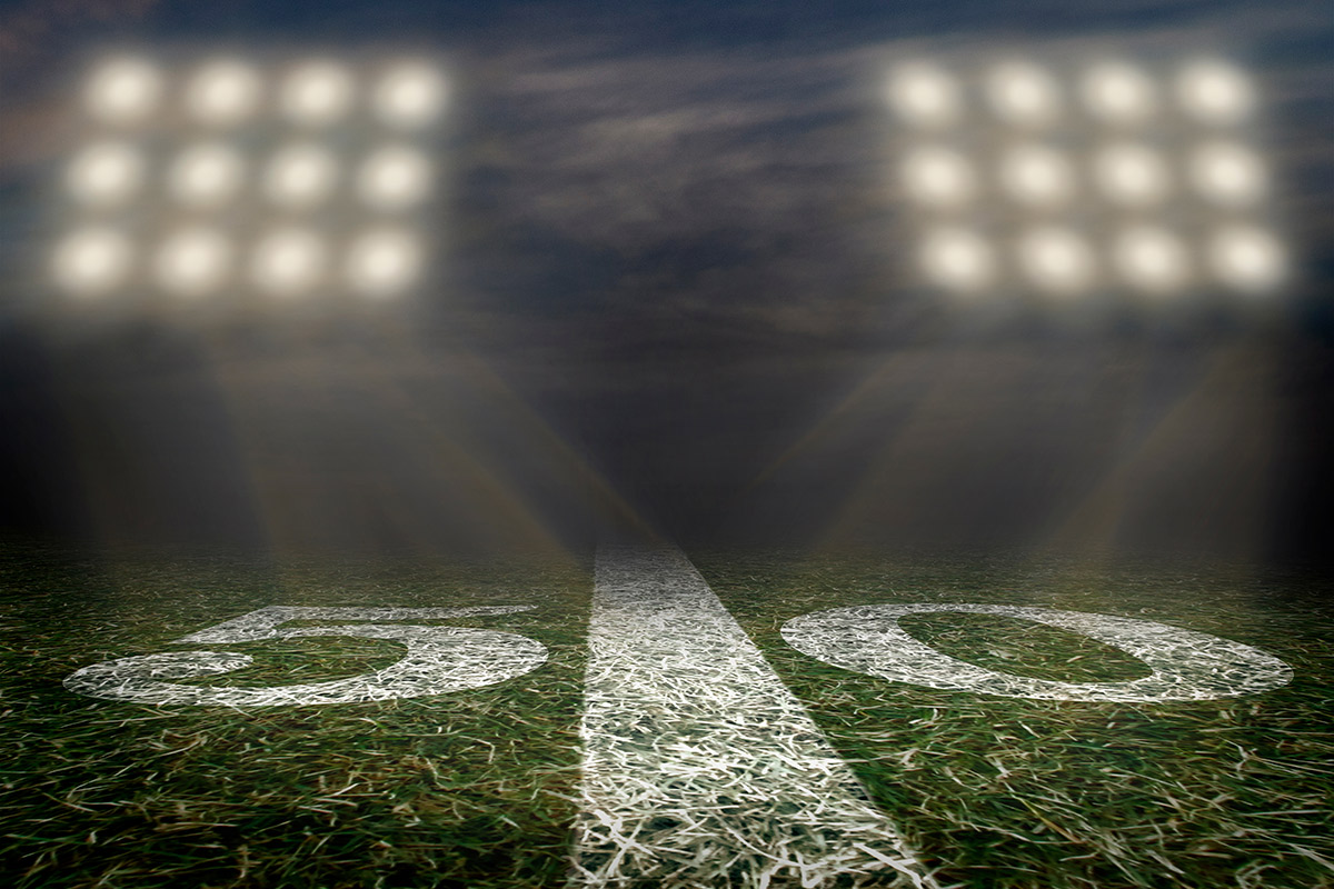 Shutterstock image of a football stadium lights and the 50 yard line