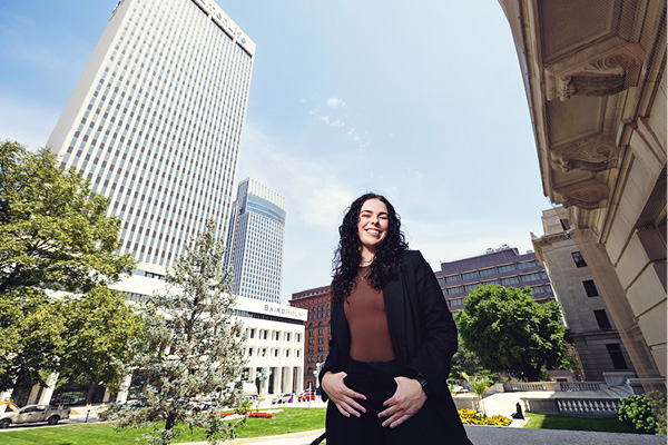 A student poses downtown near office buildings.