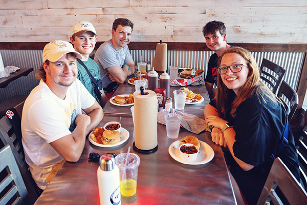 Students eat together at a restaurant booth.