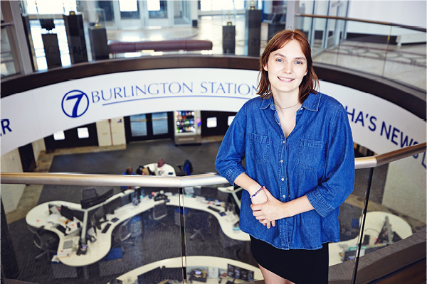 Student stands inside the Burlington Station newsroom lobby.