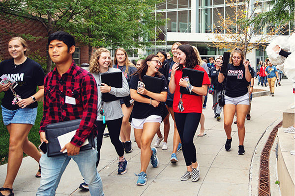 A campus tour guide leads a group of students across campus.