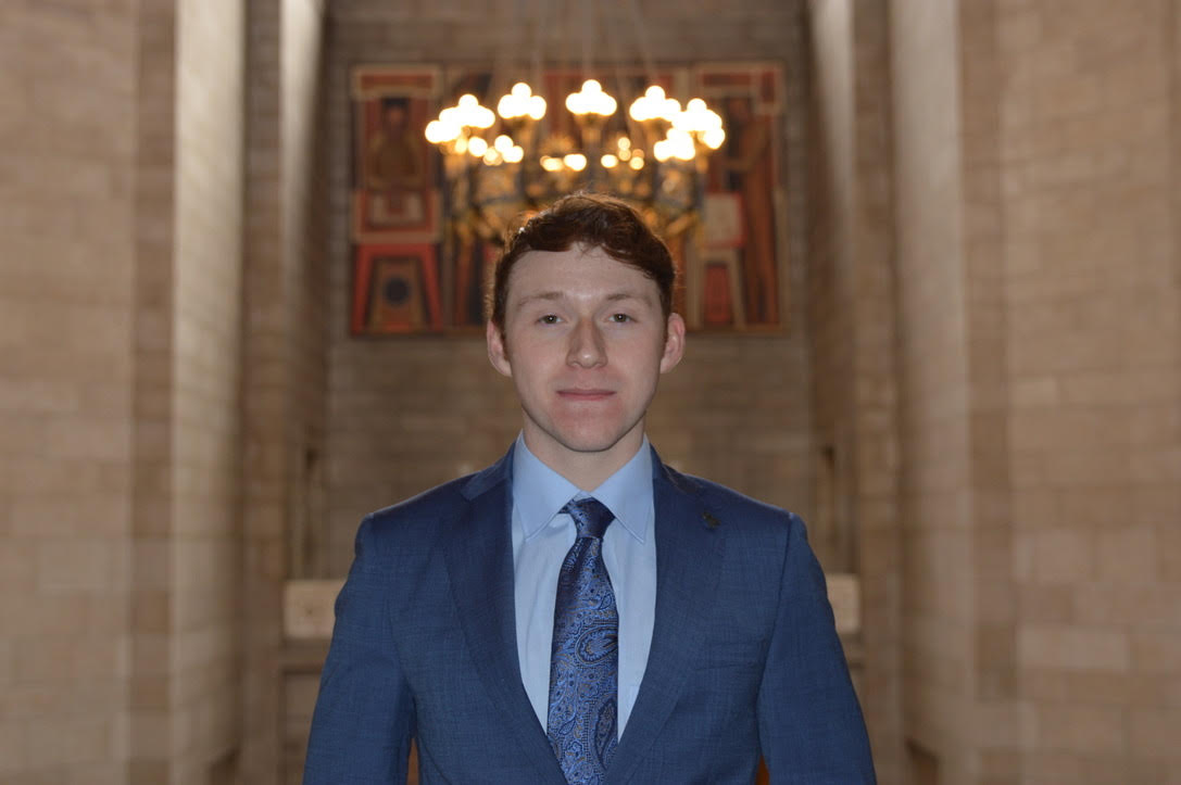 Student in suit and tie under a light in an historic government building