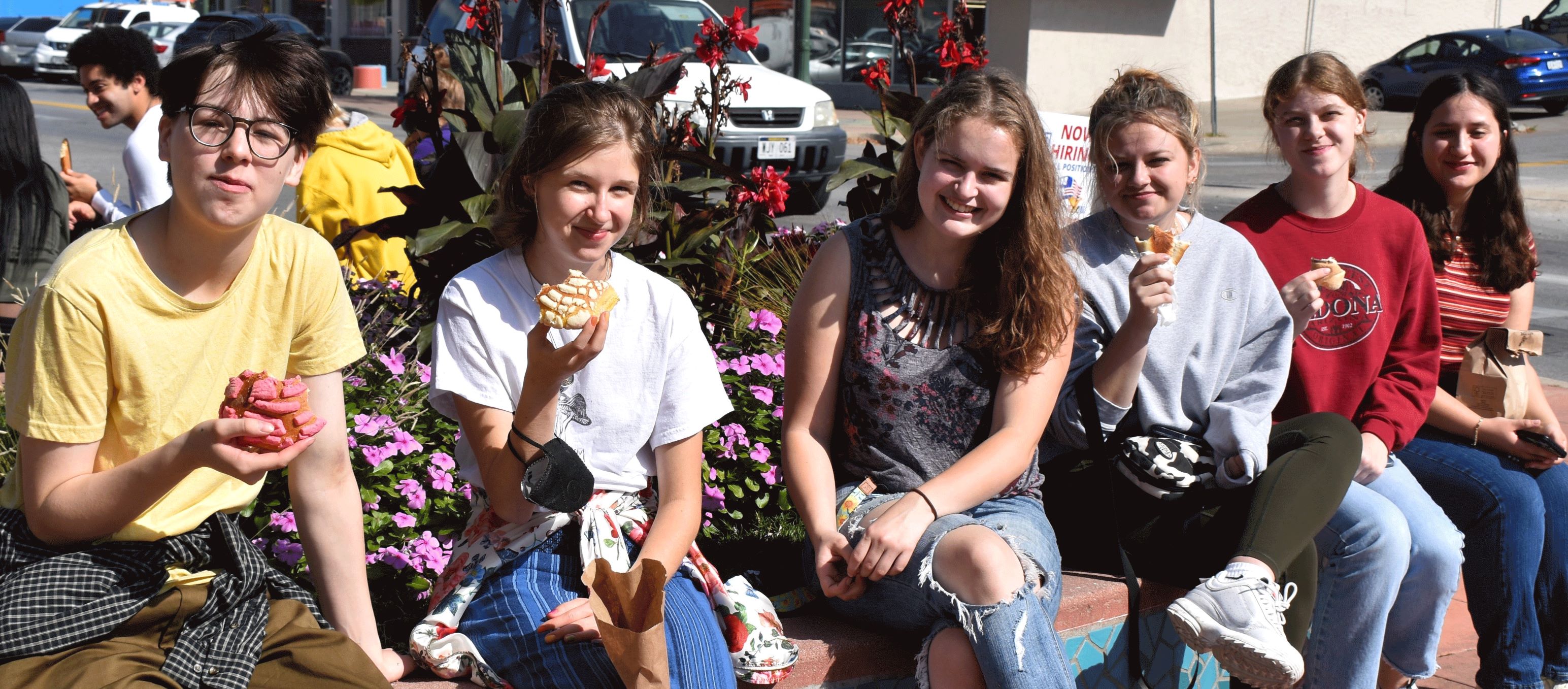 6 Honors students sitting near a street with Mexican bakery sweets in their hands