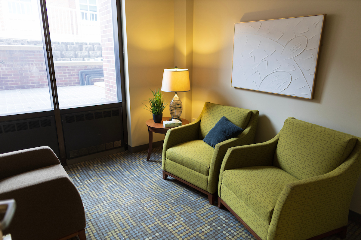 Cozy seating area with two armchairs, a side table with a lamp, and a window letting in natural light