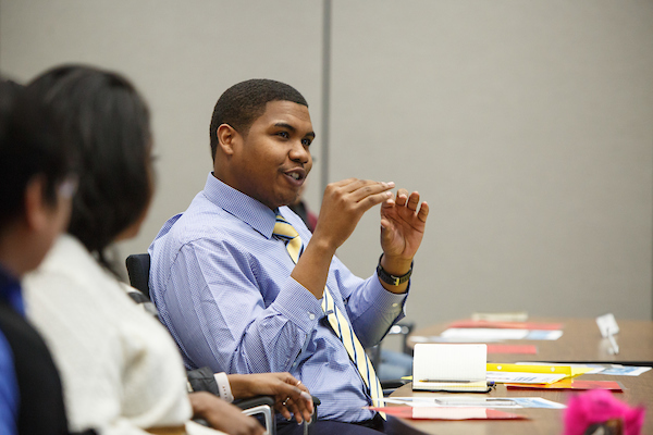 a black male student dressed professionally speaks to a classroom of students