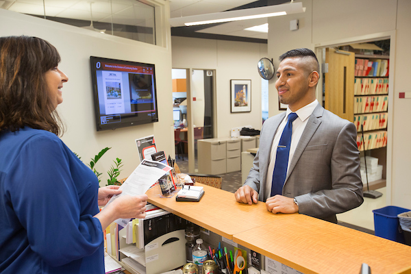 a woman talks to a man behind a counter in a medical office