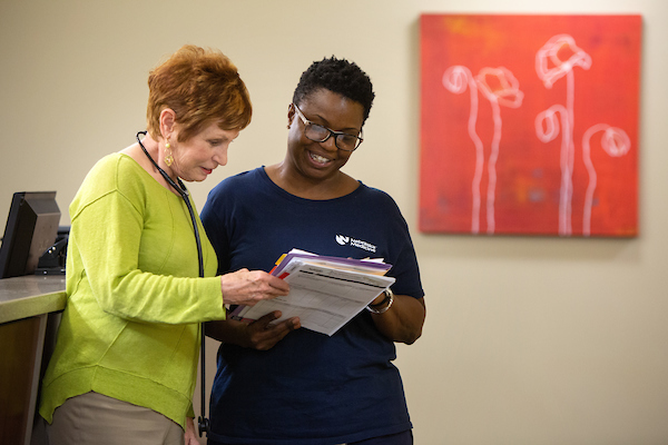 a doctor looks at a clipboard with a woman in an office