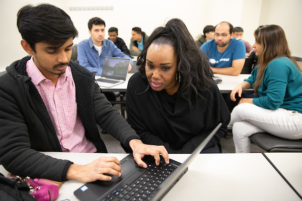 an african american woman looks at a laptop while a man types