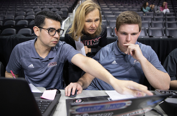 a female teacher works with two male students