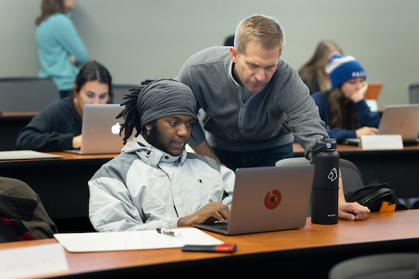 an african american man and his professor look at a laptop