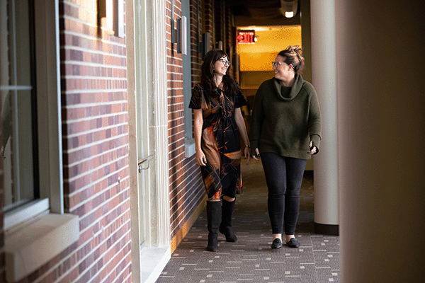 two women walk through the hall of UNO's social work building