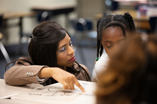 a woman works with a child at a table in a classroom