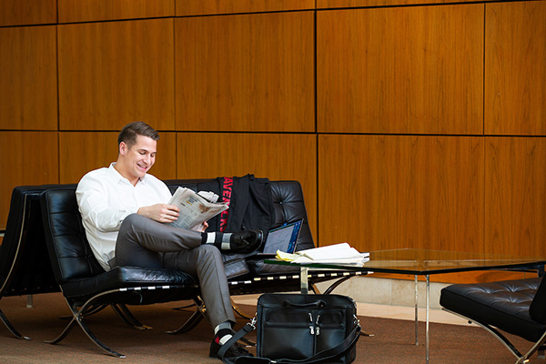 a man sits in a chair looking at a book in mammel hall