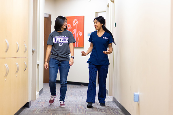 a health care worker and a student walk and talk in the UNO health care center