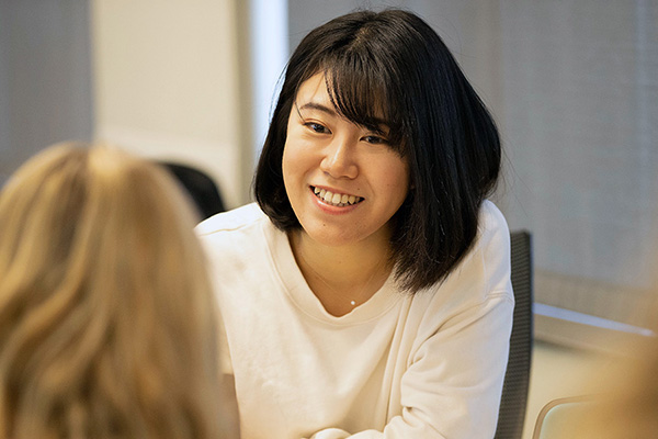 a young woman in class smiles at another classmate