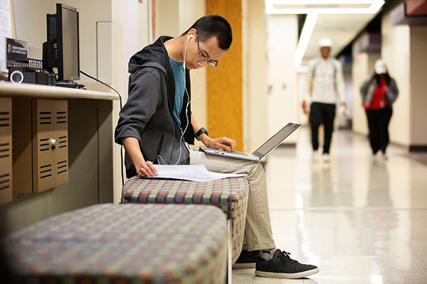 Jonathan Nguyen, a student in the School of Criminology and Criminal Justice, works in the hallway in the College of Public Administration and Community Service
