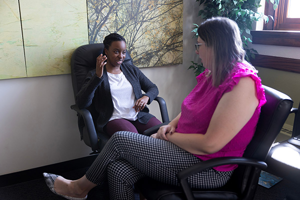 2 women sit in an office talking