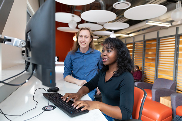 two people look at a laptop