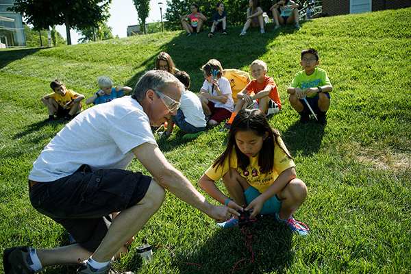 a male teacher instructs a female student in an outdoor classroom setting