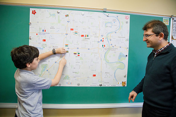 a student and a teacher point to a map taped to a chalk board