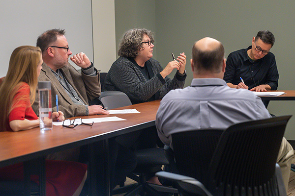 a group of people meets around a large conference table