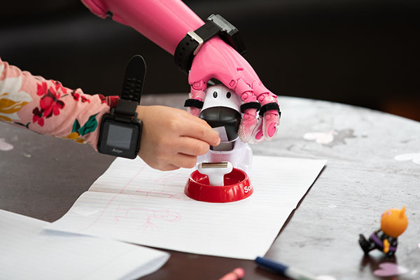 Rue Gillespie uses her prosthesis as she gets tape from a tape dispenser as Jorge M. Zuniga, Ph.D, and his team run Rue through a series of tests 