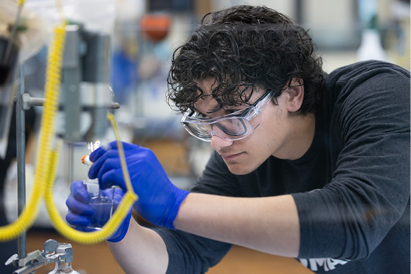 Male student looking through a microscope.