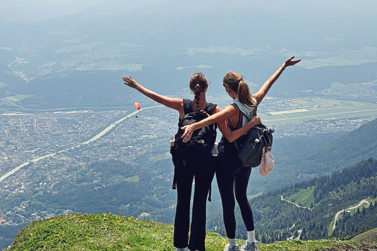 two girls standing on top of a mountain