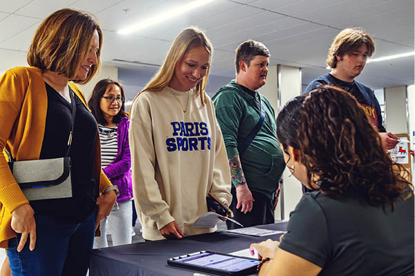 A parent and their children learning more about college at a booth.