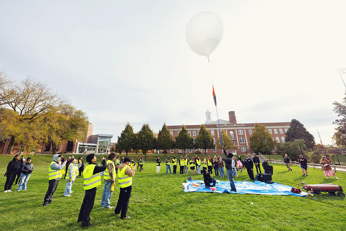 Students prepare and launch a research balloon on campus during a science project.