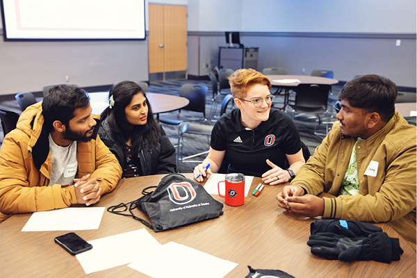 group of international students sit at a table talking to an advisor