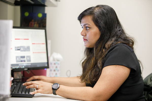 a woman works on multiple computer screens.