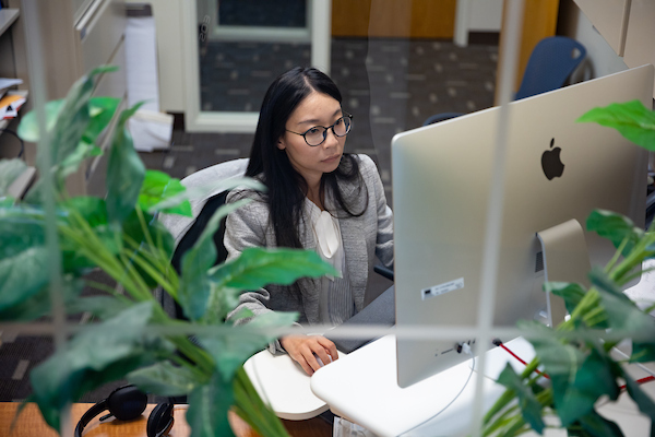 a woman works on her computer at a desk.