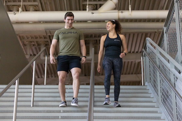 a man and woman walk down a flight of stairs.