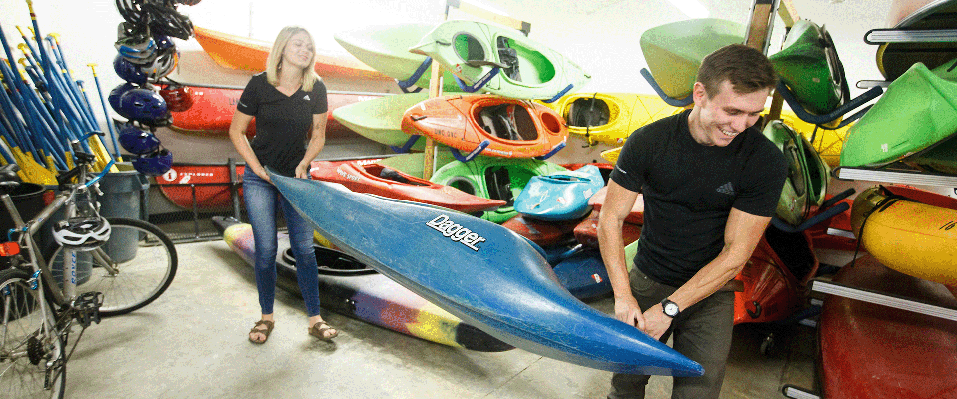 two people carry a kayak.