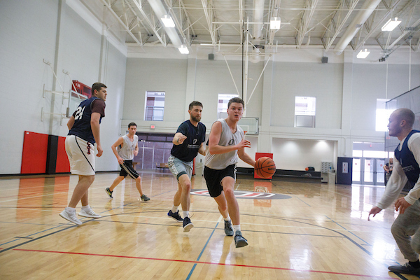 a group of men play basketball.