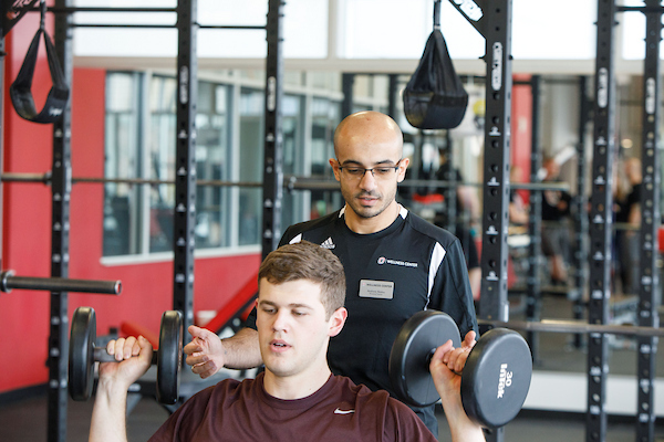 a personal trainer helps a student.