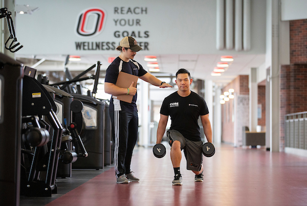 a man helps another man as he works out with weights.
