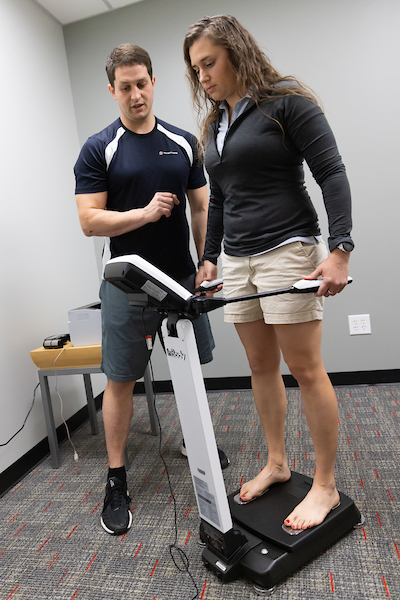 a man helps a woman with a fitness machine.